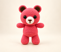 Pink handmade crochet bear with a cream muzzle on a cream background